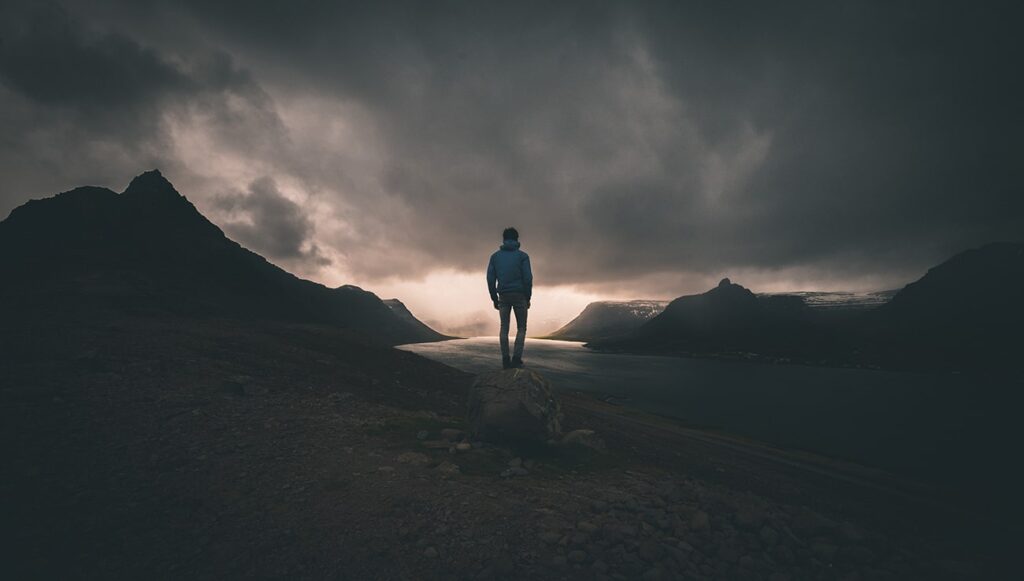 Wanderer steht bei dunklen Sturmwolken auf einem Bergrücken in Norwegen