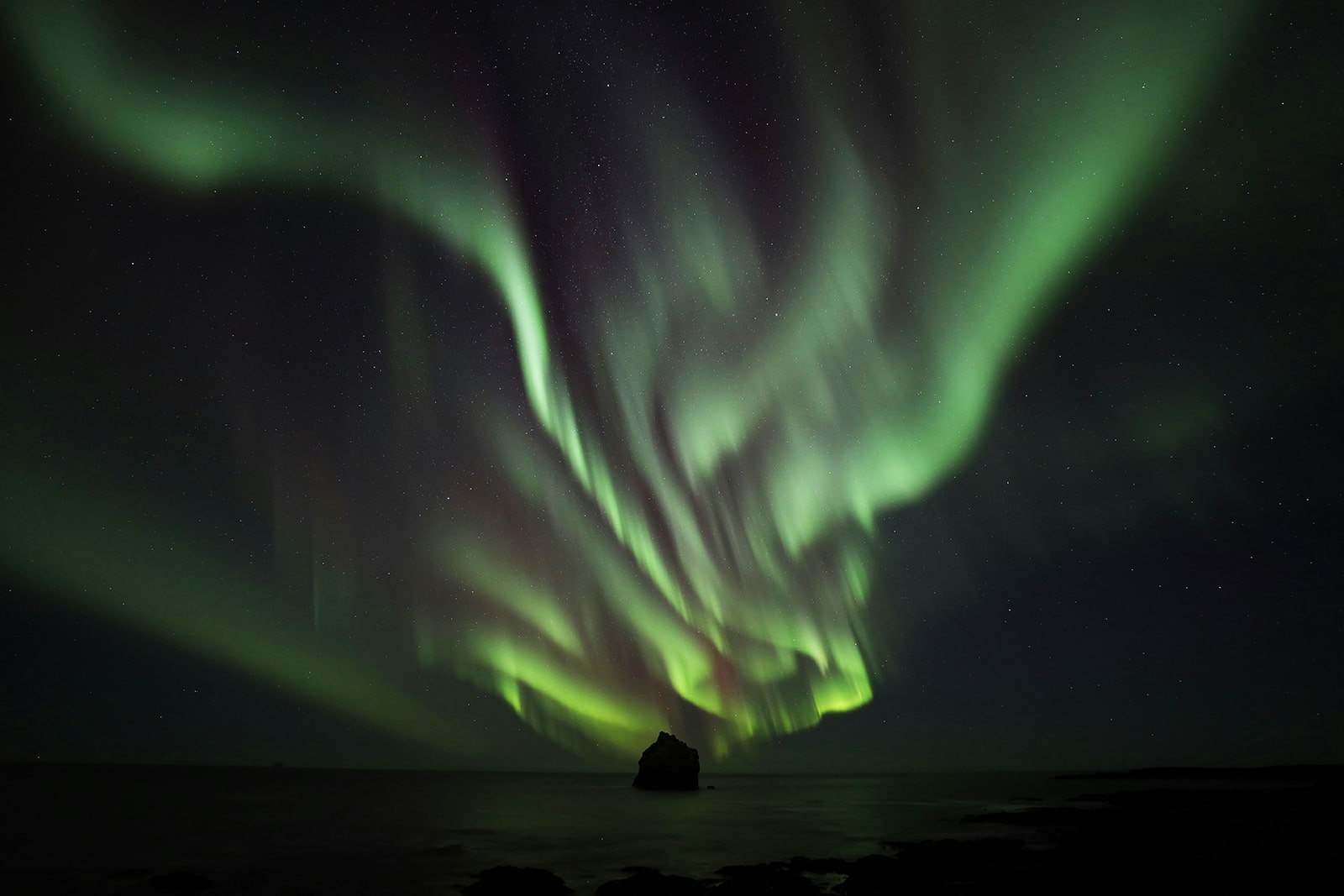 Nordlichter über dem Meer mit klarer Sternennacht.