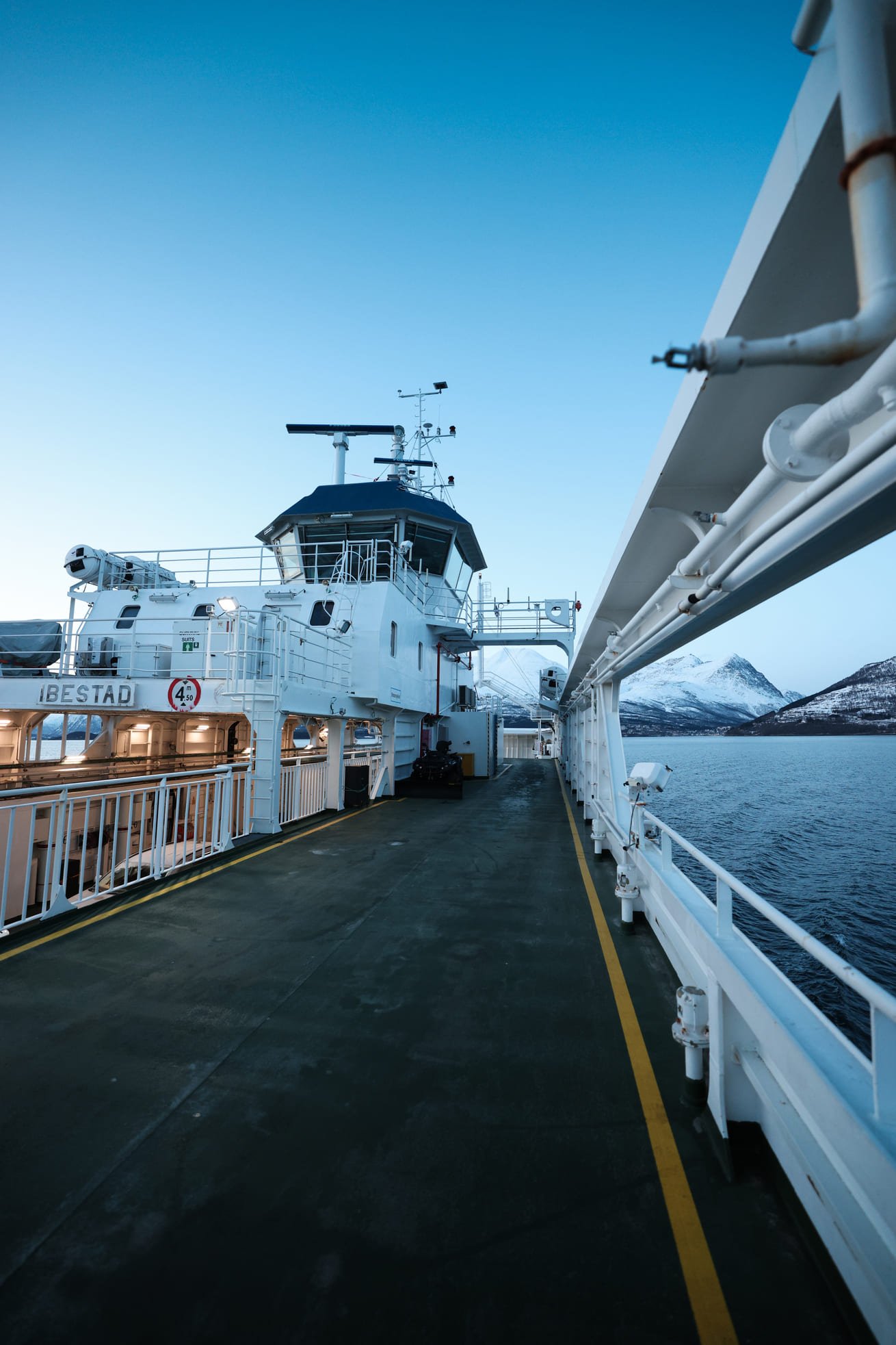 Deck der Fähre auf dem Ullsfjord, dahinter die schneebedeckten Berge der Lyngen Alps in der Dämmerung
