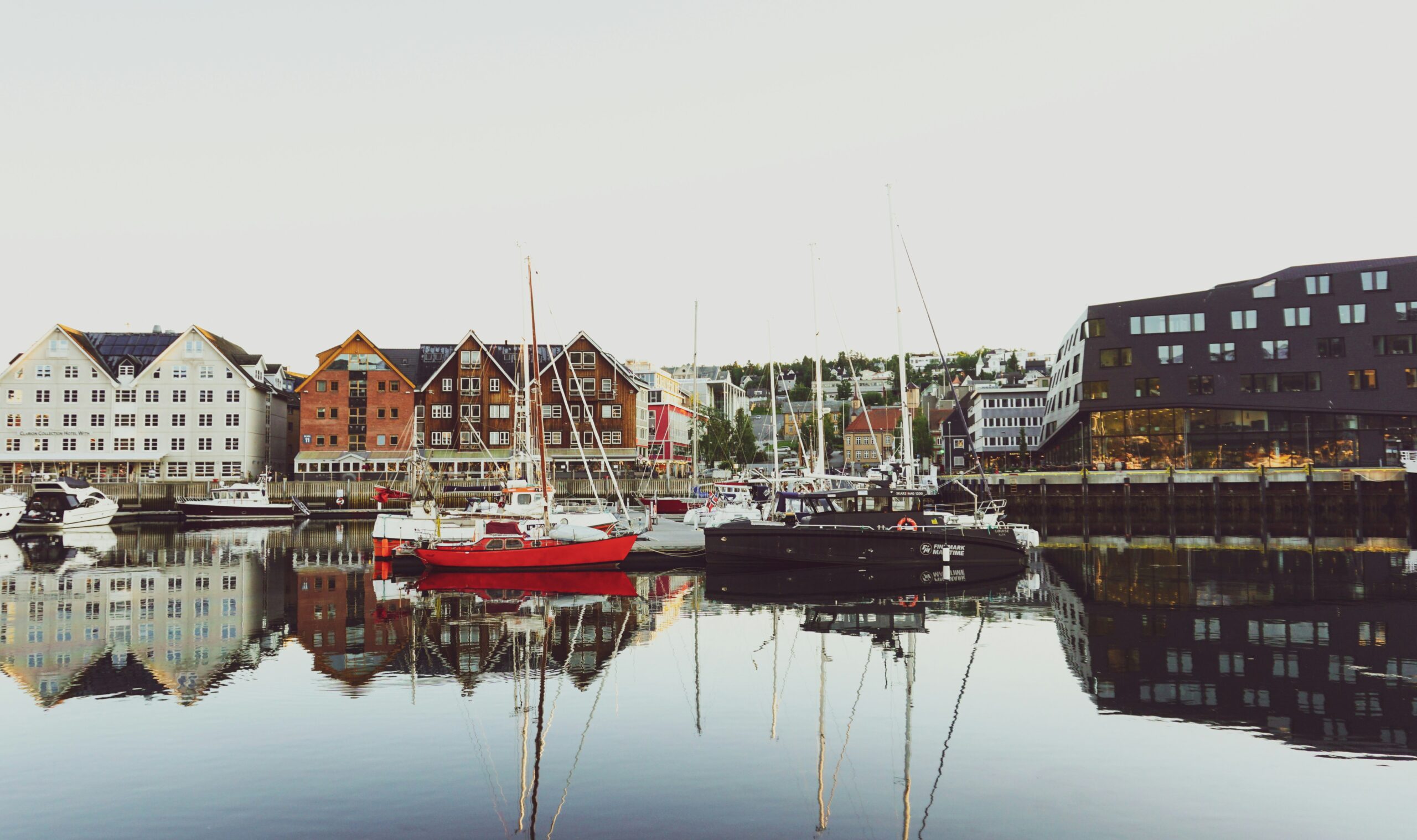 Hafen von Tromsø mit alten Holzhäusern, Segelbooten und Spiegelung im Wasser